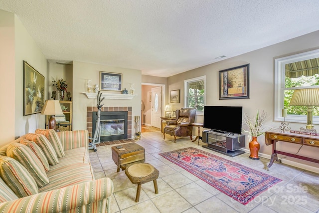 living room featuring a fireplace, light tile patterned flooring, and a textured ceiling