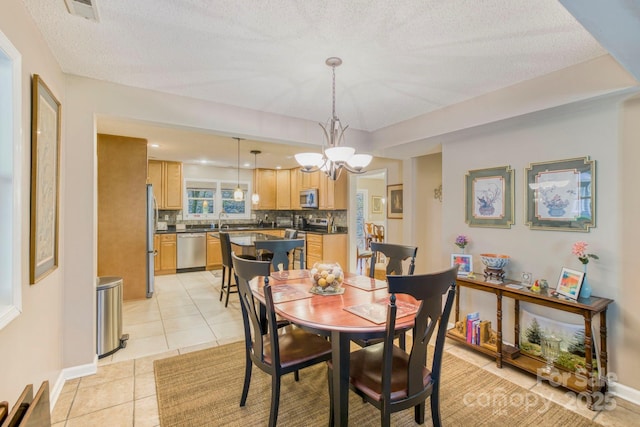 dining room with sink, a textured ceiling, and light tile patterned floors