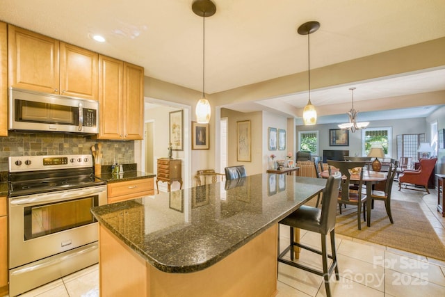 kitchen with decorative light fixtures, light tile patterned flooring, a breakfast bar, and appliances with stainless steel finishes