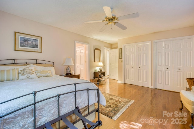 bedroom featuring multiple closets, hardwood / wood-style flooring, and ceiling fan