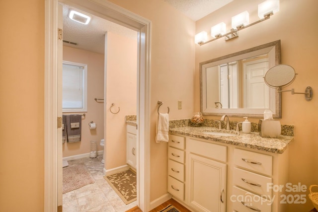 bathroom with a textured ceiling, toilet, and vanity