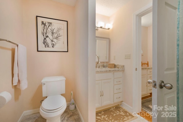 bathroom with vanity, toilet, and a textured ceiling