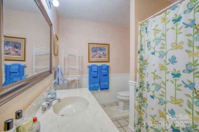 bathroom with toilet, a textured ceiling, tile patterned floors, and vanity