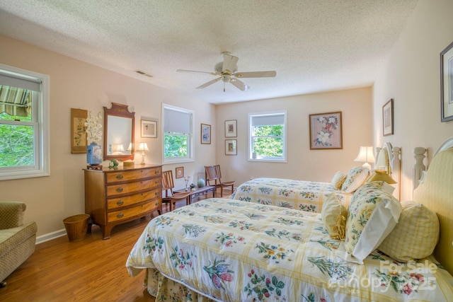 bedroom featuring a textured ceiling, light hardwood / wood-style flooring, and ceiling fan