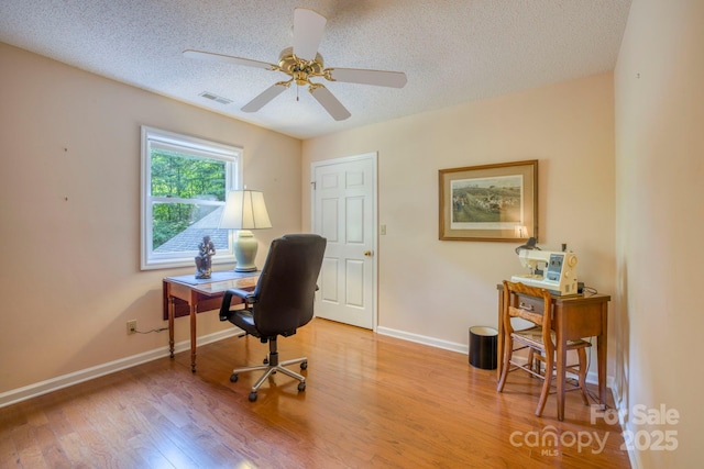 home office featuring light wood-type flooring, a textured ceiling, and ceiling fan