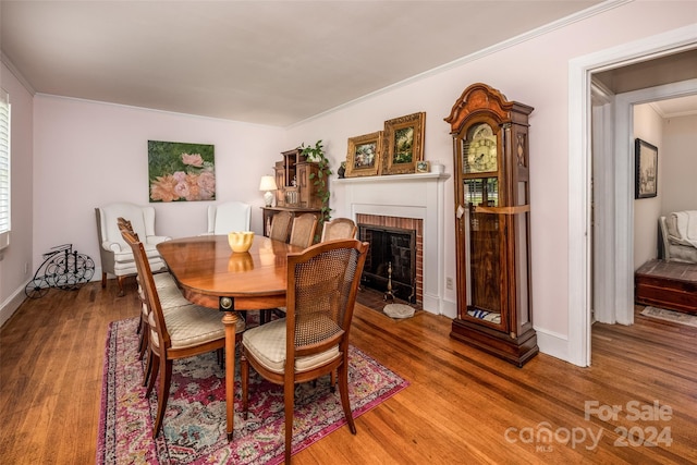 dining area featuring a brick fireplace, crown molding, and hardwood / wood-style flooring