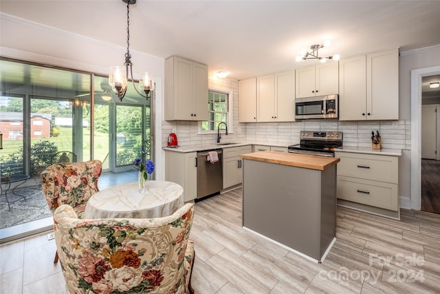 kitchen featuring white cabinets, appliances with stainless steel finishes, a center island, butcher block counters, and sink