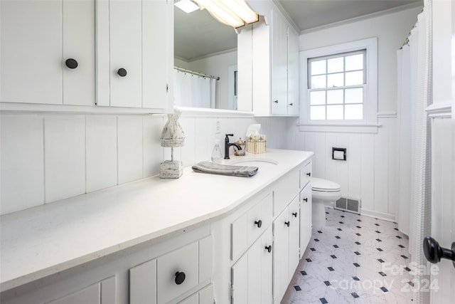 bathroom with toilet, vanity, and ornamental molding