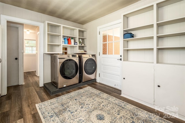 clothes washing area featuring dark hardwood / wood-style floors, wood walls, and washing machine and clothes dryer