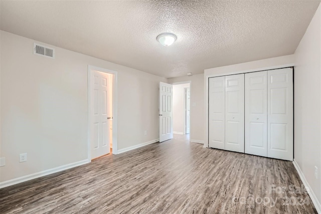 unfurnished bedroom featuring a textured ceiling, hardwood / wood-style flooring, and a closet