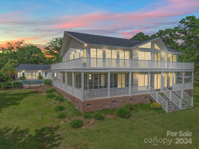 back house at dusk featuring a yard and a sunroom