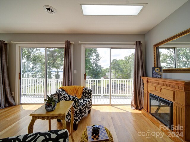 living room featuring a healthy amount of sunlight, a skylight, and light hardwood / wood-style floors