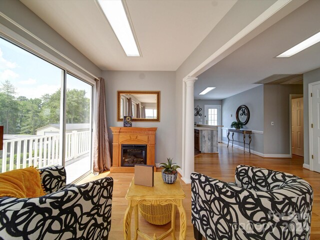 living room featuring a skylight, hardwood / wood-style flooring, and ornate columns