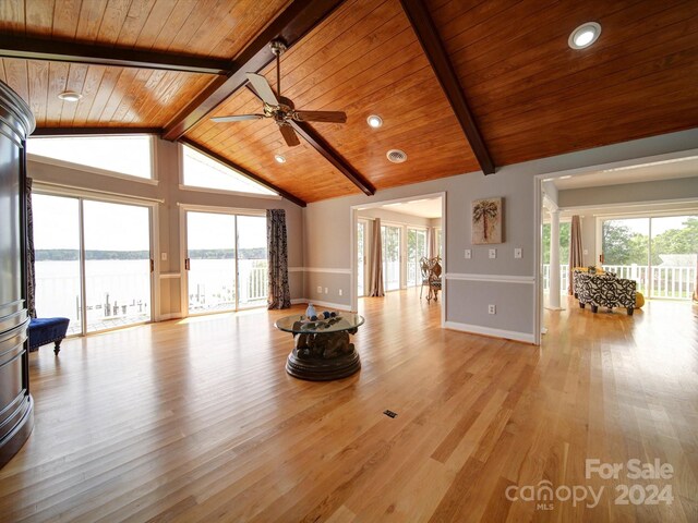 unfurnished living room featuring wooden ceiling, light wood-type flooring, a water view, and vaulted ceiling with beams