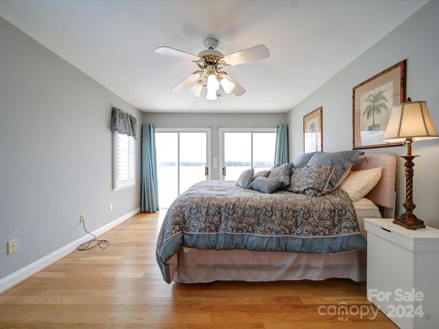 bedroom with ceiling fan, access to outside, a water view, and light wood-type flooring