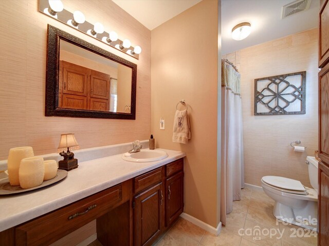 bathroom with toilet, vanity, walk in shower, and tile patterned flooring