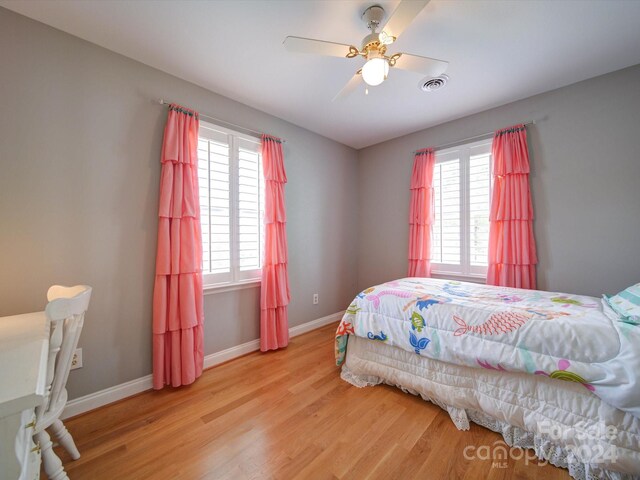 bedroom featuring ceiling fan, multiple windows, and light hardwood / wood-style floors