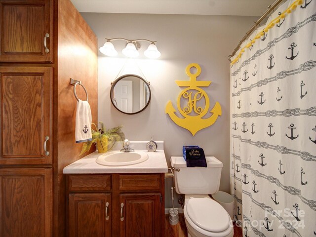 bathroom featuring toilet, vanity, and a shower with curtain