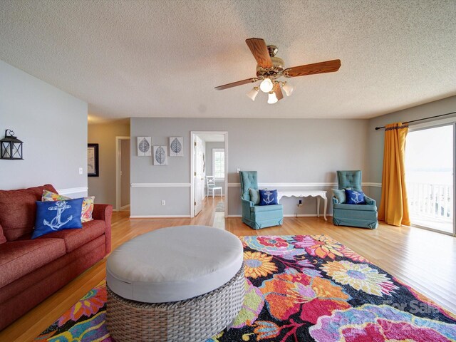 living room with ceiling fan, a textured ceiling, and hardwood / wood-style floors