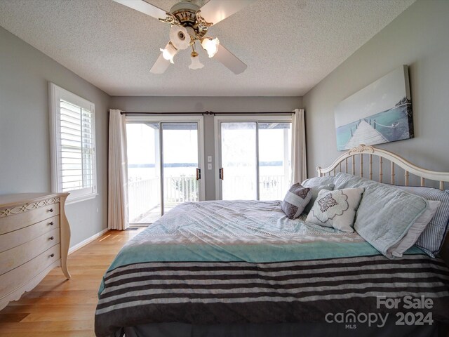 bedroom with light wood-type flooring, ceiling fan, access to exterior, and a textured ceiling