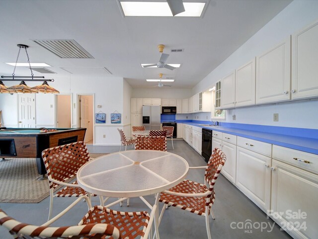 kitchen with black appliances, white cabinets, a skylight, and pendant lighting