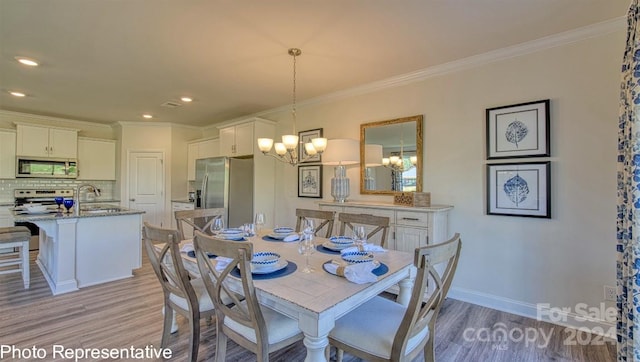 dining area featuring crown molding, light hardwood / wood-style flooring, sink, and an inviting chandelier