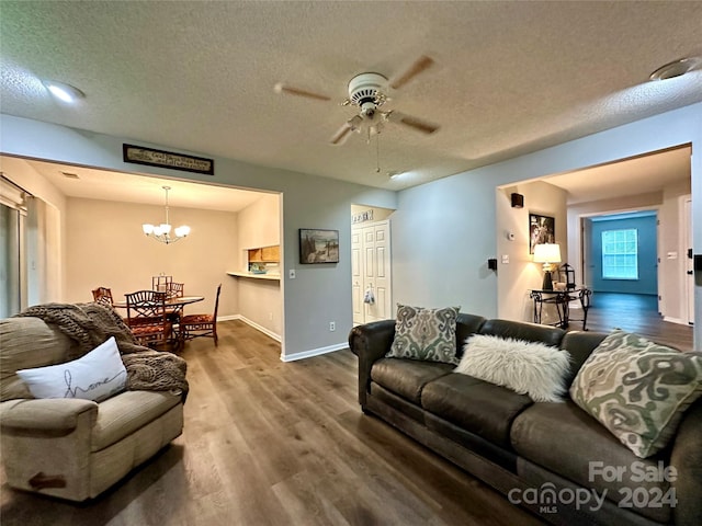 living room with ceiling fan with notable chandelier, wood-type flooring, and a textured ceiling