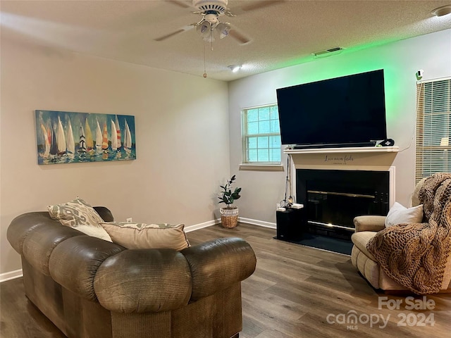 living room with ceiling fan, wood-type flooring, and a textured ceiling