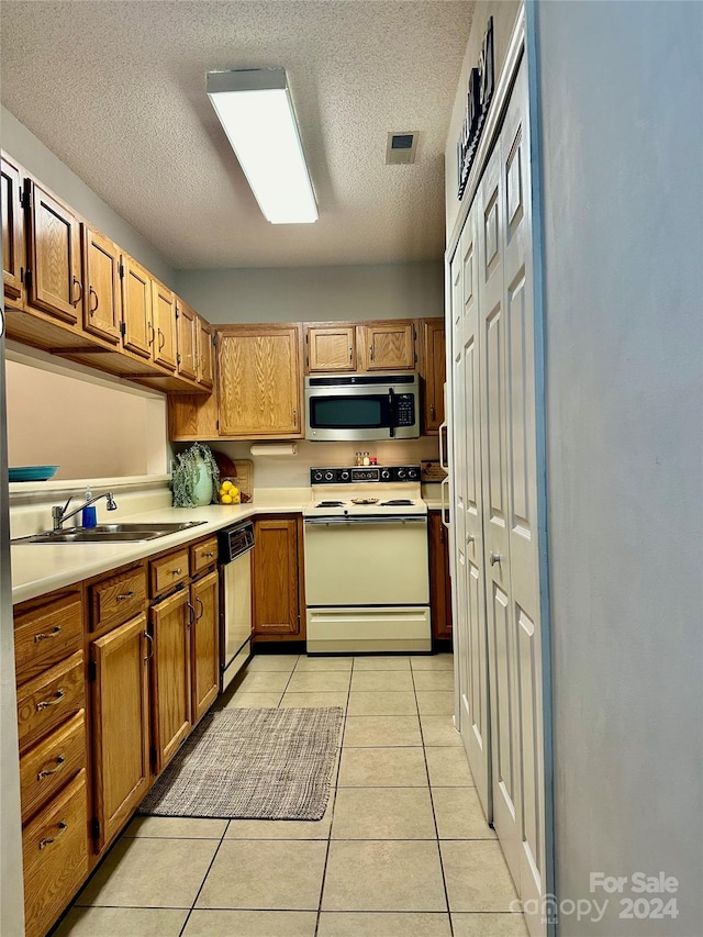 kitchen with light tile patterned floors, a textured ceiling, stainless steel appliances, and sink