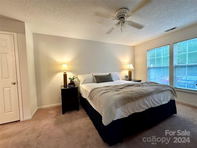 bedroom with carpet flooring, ceiling fan, and a textured ceiling