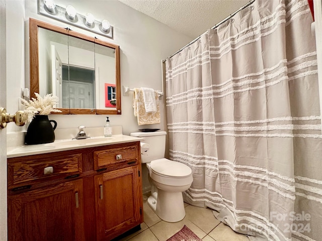 bathroom featuring tile patterned flooring, vanity, a textured ceiling, and toilet