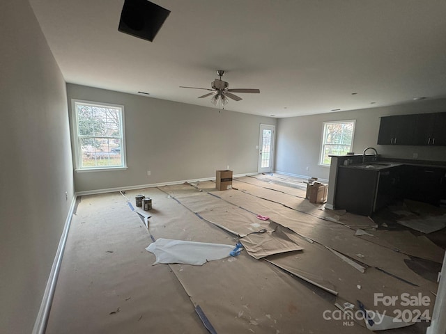 unfurnished living room featuring plenty of natural light, ceiling fan, and sink