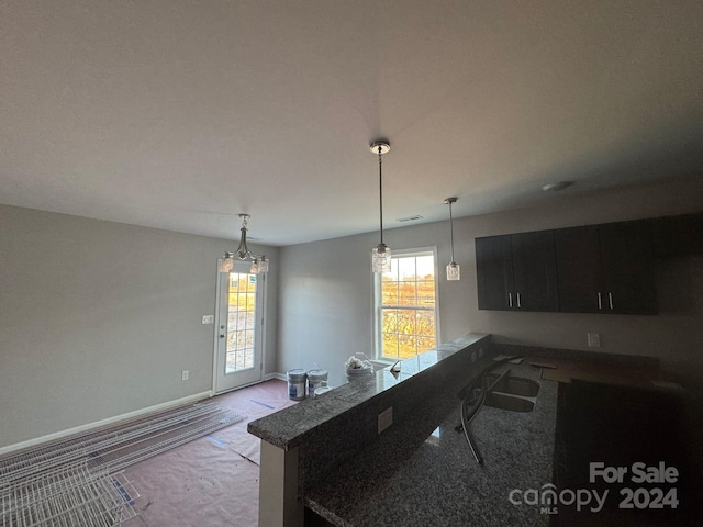 kitchen featuring a healthy amount of sunlight, light colored carpet, kitchen peninsula, and hanging light fixtures