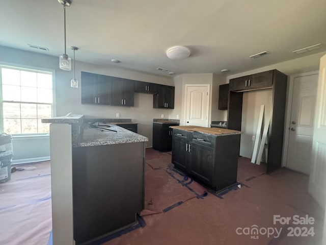 kitchen featuring kitchen peninsula, pendant lighting, and light stone counters