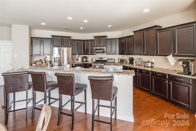 kitchen with a kitchen bar, appliances with stainless steel finishes, and a center island with sink