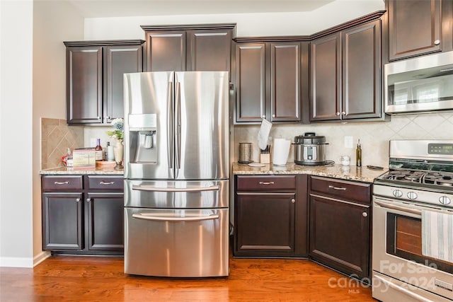 kitchen featuring appliances with stainless steel finishes, tasteful backsplash, and dark wood-type flooring