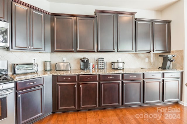 kitchen featuring light stone countertops, stainless steel appliances, tasteful backsplash, light hardwood / wood-style flooring, and dark brown cabinets