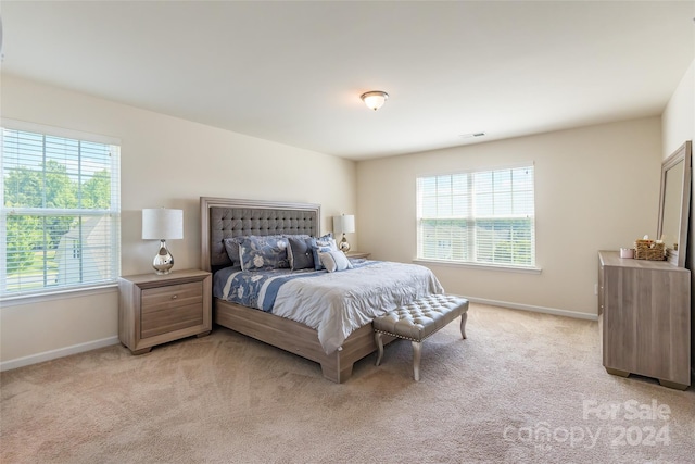 bedroom with light carpet and multiple windows