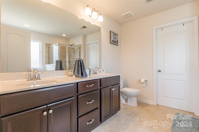 bathroom featuring tile patterned flooring, vanity, toilet, and a shower with shower door