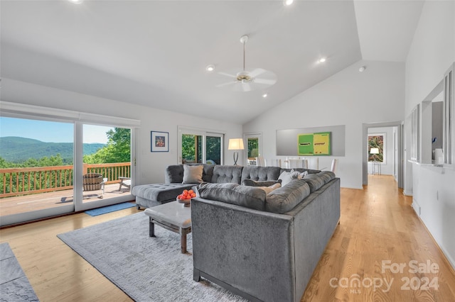 living room with a mountain view, ceiling fan, light hardwood / wood-style floors, and high vaulted ceiling