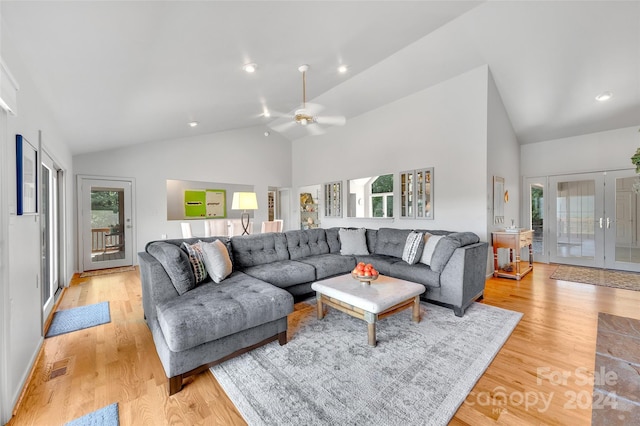 living room with ceiling fan, high vaulted ceiling, and light wood-type flooring