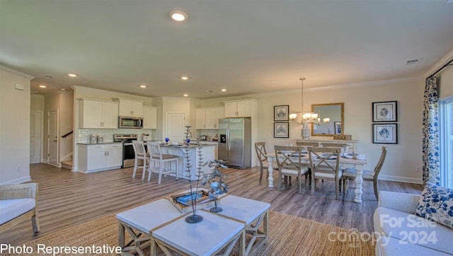 living room featuring light hardwood / wood-style floors, ornamental molding, and a chandelier