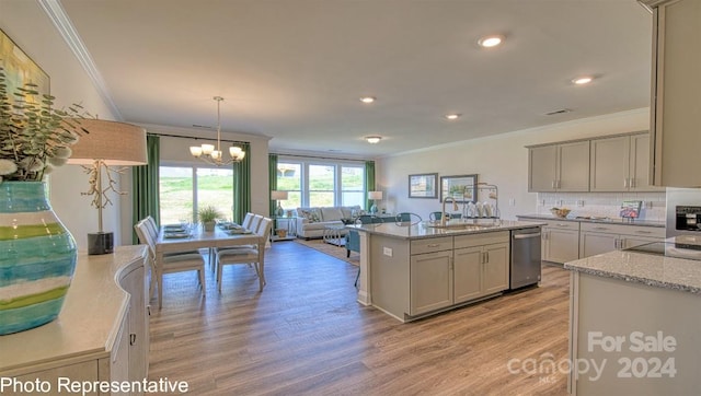 kitchen featuring a kitchen island with sink, sink, hanging light fixtures, stainless steel dishwasher, and light hardwood / wood-style floors