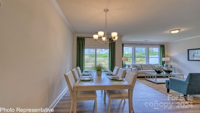 dining space with crown molding, hardwood / wood-style floors, and a notable chandelier