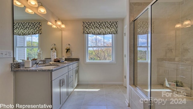 bathroom featuring tile patterned flooring, vanity, a shower with door, and a wealth of natural light