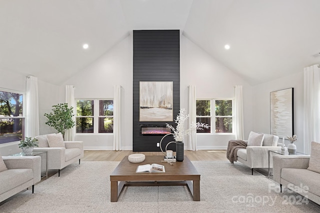 living room with light wood-type flooring, a large fireplace, and high vaulted ceiling