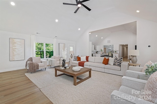 living room with ceiling fan, light hardwood / wood-style floors, and high vaulted ceiling