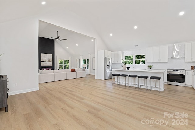 living room with ceiling fan, high vaulted ceiling, and light hardwood / wood-style flooring