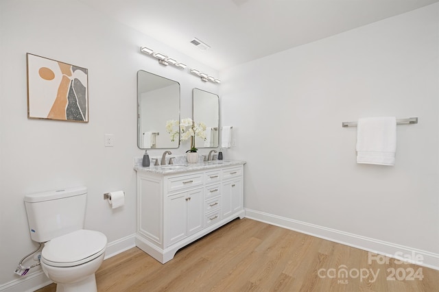 bathroom with hardwood / wood-style floors, vanity, and toilet