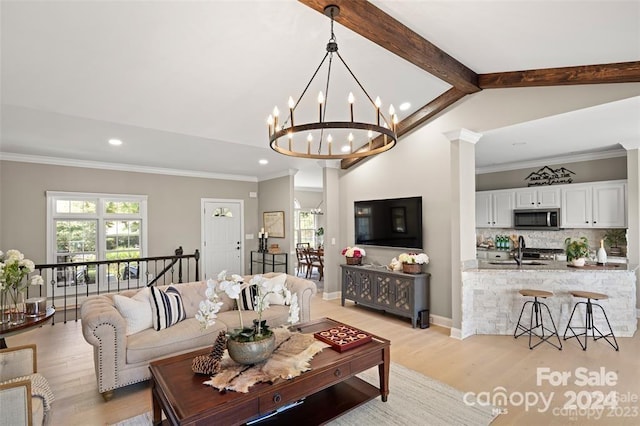 living room with a notable chandelier, light hardwood / wood-style floors, crown molding, and lofted ceiling with beams